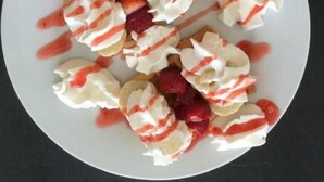 A white plate with whipped cream and strawberries, drizzled with a red sauce. - Canigou Et Jo room with shared garden, Wi-Fi and air conditioning (Perpignan)