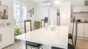 A modern kitchen with a central island, white cabinetry, and a dining area with chairs. - Canigou Et Jo room with shared garden, Wi-Fi and air conditioning (Perpignan)