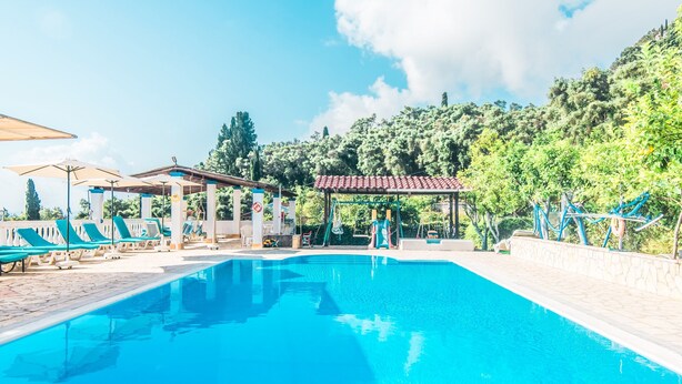 A swimming pool with lounge chairs, a gazebo, and a view of a forested hillside. - Apartment 'Andromaches Single Studio' with Sea View, Wi-Fi and Air Conditioning (Corfu)