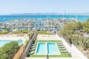 Un port de plaisance abritant de nombreux bateaux, une piscine et un espace aménagé avec des chaises.