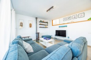 Uma sala de estar moderna com um conjunto de sofás, uma mesa de centro, uma televisão e uma lareira.
