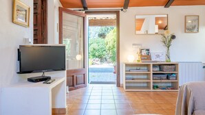 Una sala de estar con televisor, estanterías de madera, un espejo y una puerta que da al exterior.