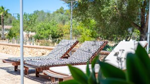 Sillones de exterior con cojines estampados, un poste de metal y una pared de piedra.