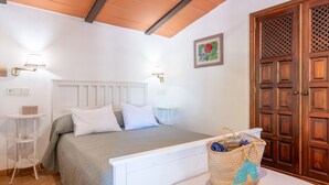 Un dormitorio con cama, mesitas de noche, una puerta de madera y una lámpara de pared.