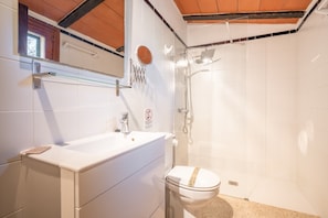 Un baño con lavamanos, inodoro y ducha blancos.