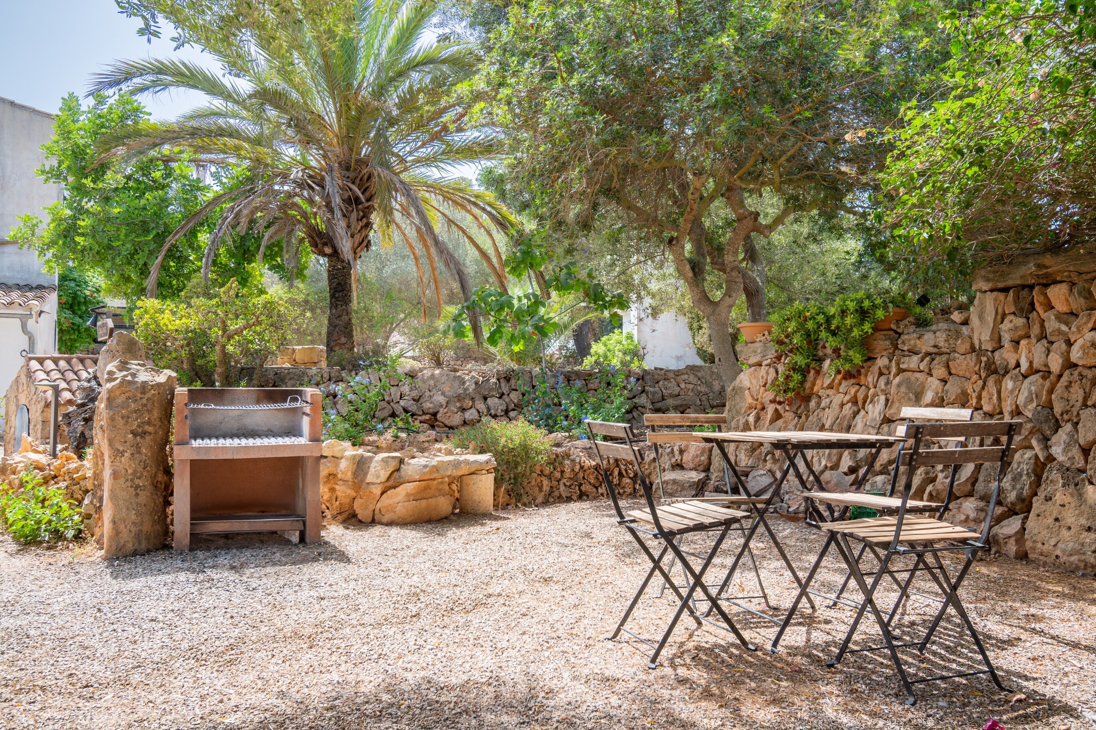 Un patio con una parrilla, pared de piedra y mobiliario exterior.