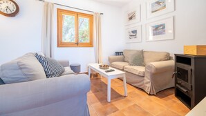 Una sala de estar con dos sofás, una mesa de centro, un reloj, una ventana con cortinas e imágenes enmarcadas en la pared.