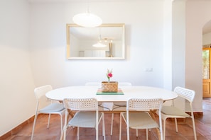 A dining area with a round table, white chairs, a hanging light fixture, and a mirror on the wall. - Farmhouse 'Sa Bassa Crua Agroturismo 3' with Shared Pool, Private Terrace and Wi-Fi (Llucmajor)
