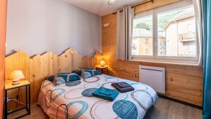 Una camera da letto con un letto, due lampade sui comodini, una finestra con tende e una parete in legno.