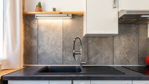 Una cucina moderna con lavello in acciaio inossidabile, forno integrato e piano di lavoro in legno.