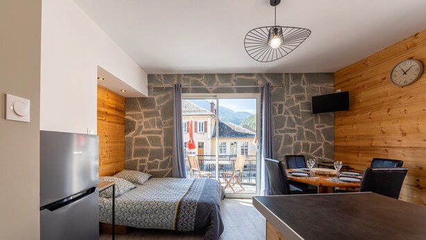 Una camera da letto moderna con un letto, un angolo ristoro, una TV e vista sull'esterno.