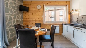 Zona pranzo con tavolo in legno, sedie e un orologio appeso al muro.