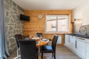 A dining area with a wooden table, chairs, and a clock on the wall.