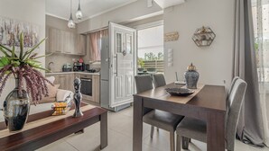 Una cocina moderna con armarios de madera, un comedor con mesa y sillas de madera, y vistas al exterior.