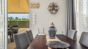 Un comedor con una mesa de madera, sillas grises, un florero decorativo y un estante hexagonal con objetos.