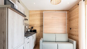 A compact kitchen with modern appliances, a built-in bench, and wooden paneling. - Apartment 'Le Chaussy' with Mountain View, Balcony and Wi-Fi (Saint-Etienne-de-Cuines)