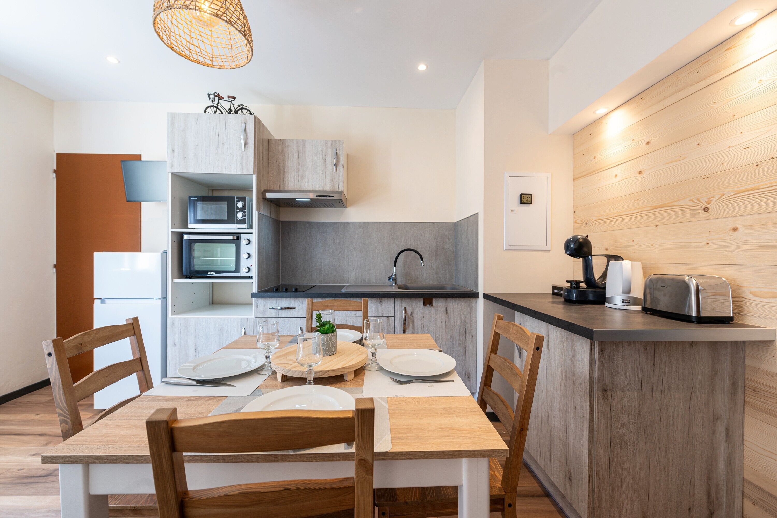Une cuisine moderne avec des meubles en bois, une table à manger avec des chaises et un four encastré.