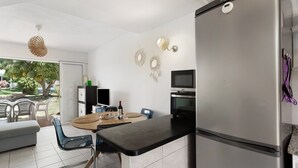 Una cocina moderna con un refrigerador de acero inoxidable, un comedor con una mesa redonda, sillas y un televisor.