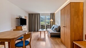 Una habitación moderna con una mesa de comedor de madera, sillas, un sofá, un televisor y un armario.