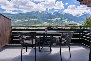 Un balcon avec deux chaises et une table, donnant sur un paysage montagneux.