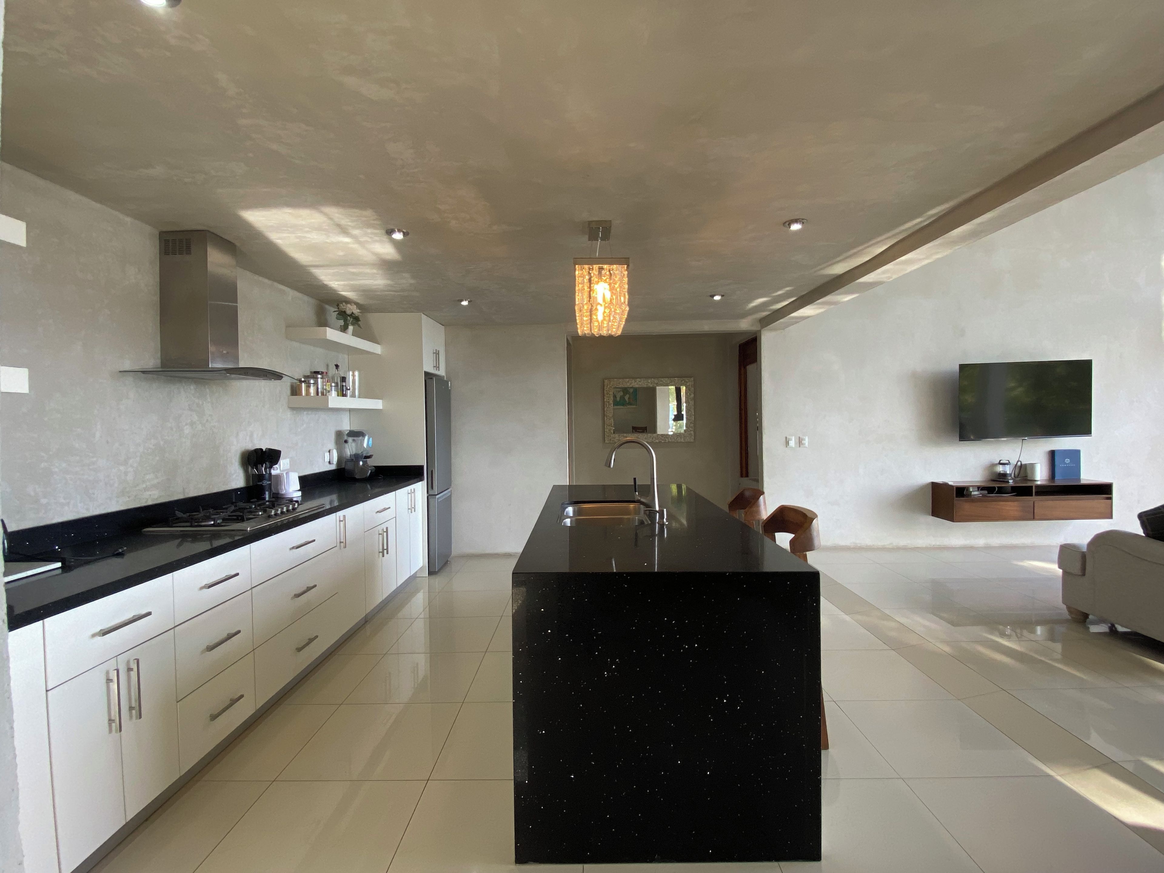 Una cocina moderna con una isla central, electrodomésticos de acero inoxidable y un televisor de pantalla plana montado en la pared.