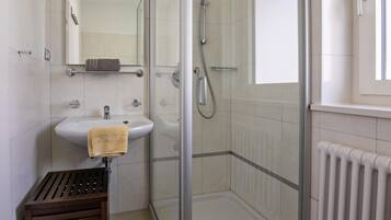 A bathroom with a glass-enclosed shower, a sink, and a towel rack.