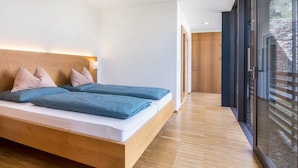 Um quarto moderno com uma cama de madeira, mesa de cabeceira e uma janela grande.