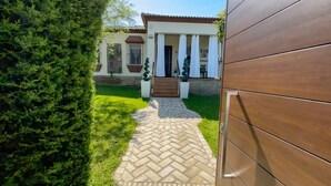 Un chemin menant à une maison avec un porche carrelé, une véranda et une pelouse bien entretenue.