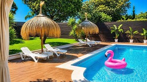 Une piscine avec des chaises longues et un flotteur en forme de flamant rose.