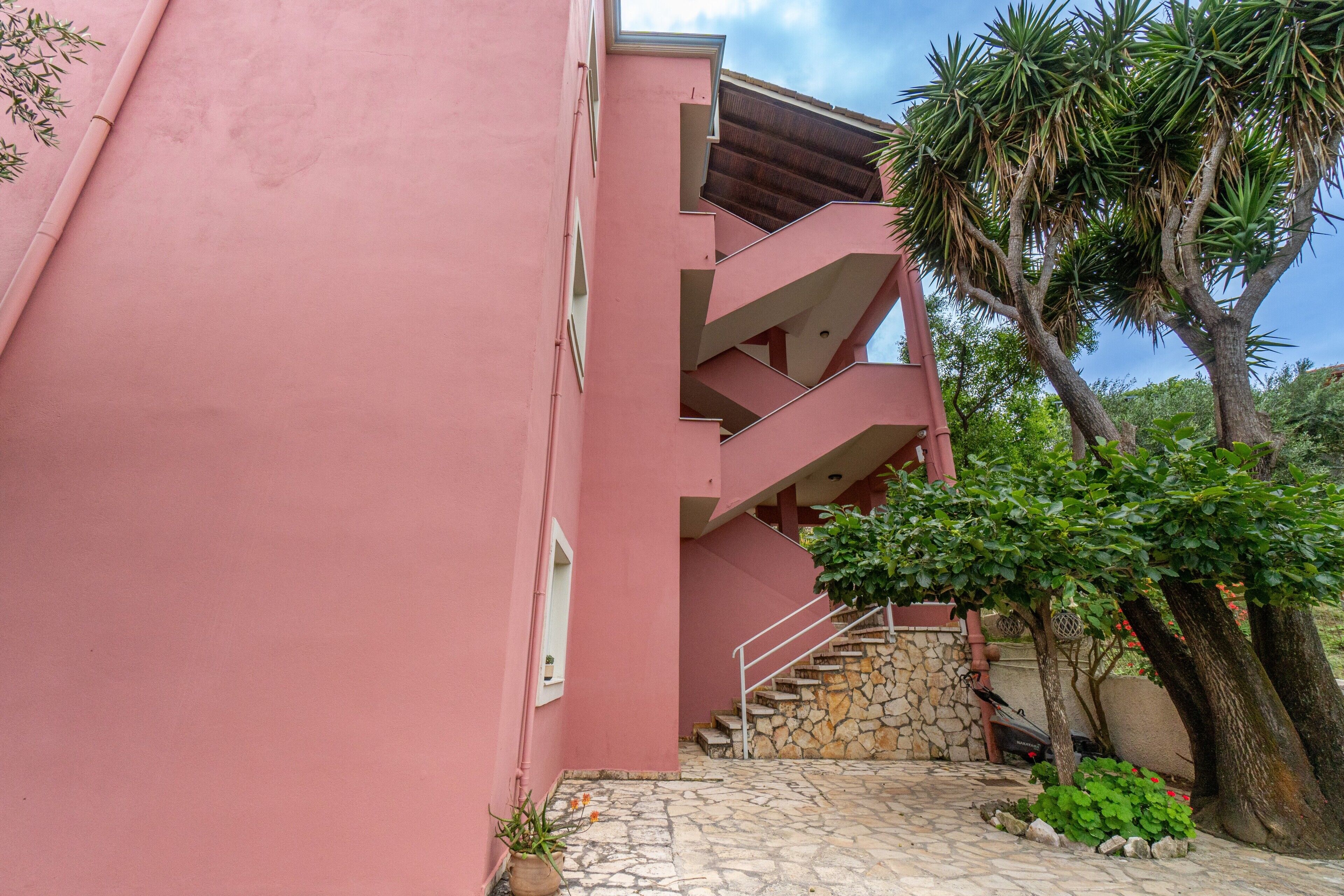 A pink building with a stone staircase leading to a balcony.