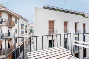 A modern building with a balcony, a staircase, and a view of a narrow street.