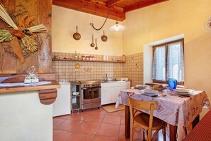 A kitchen with a stove, oven, and hanging pots.