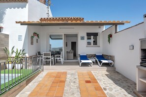 A patio with a dining area, a sofa, and a grill.