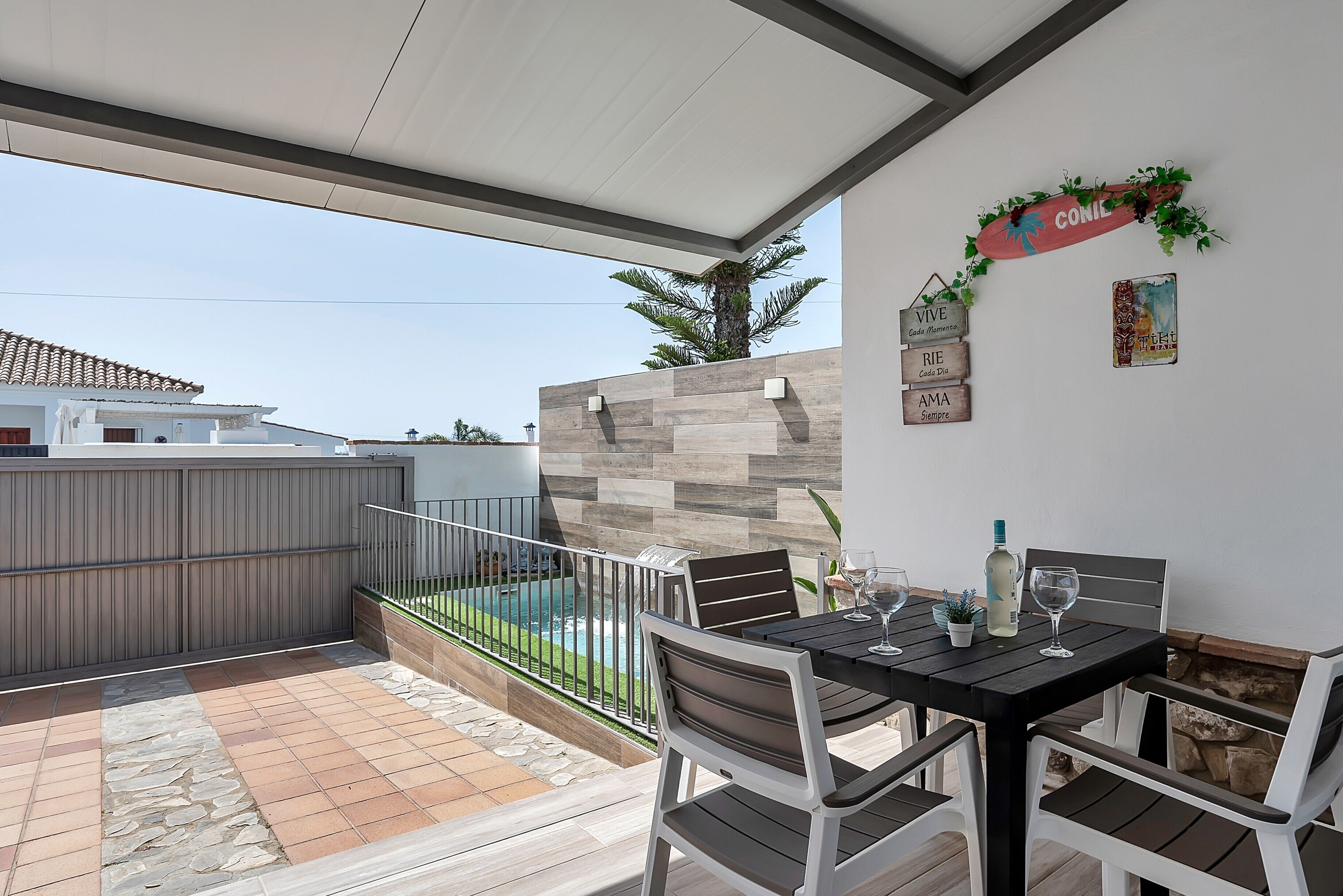 Un patio cubierto con piscina, mobiliario exterior y detalles decorativos en la pared.