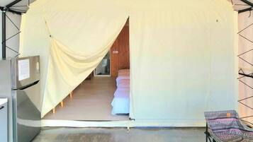 A tented room with a bed, a small table, and a hanging light fixture.