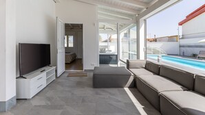 A modern living room with a flat-screen TV, a sofa, and a pool view. - Villa 'Maria Con Piscina Riscaldata' with Sea View, Wi-Fi and Air Conditioning (Santa Maria del Focallo)