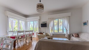 Une pièce comprenant un lit, une table à manger avec des chaises, un téléviseur et une fenêtre avec des rideaux.