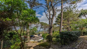 Un chemin pavé mène à un bâtiment d’où l’on a une vue sur la mer.