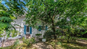 Un bâtiment blanc avec des volets bleus et un patio aménagé avec du mobilier d’extérieur.