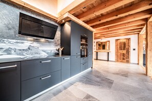 Une cuisine moderne avec des meubles de couleur sombre, un four à micro-ondes encastré et une grande fenêtre donnant sur les montagnes.