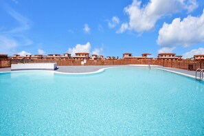 Une piscine entourée d’une clôture en bois, sous un ciel bleu et dégagé.