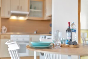Een keuken met een eettafel, een fles wijn, glazen en een bord koekjes.