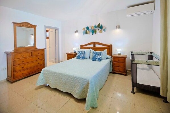 Een slaapkamer met een bed, een dressoir, nachtkastjes en een airconditioning.