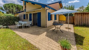A house with a patio, a table with chairs, and a potted plant. - Holiday Home 'Maison Océlandes' with Shared Pool, Private Terrace and Wi-Fi (Saint-Julien-en-Born)