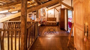 Een houten zolderkamer met een schuine kap, een kamerbreed tapijt met dessin en een houten garderobekast.