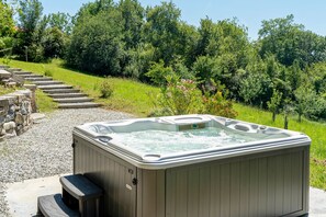 Un jacuzzi en un entorno de jardín con escalones que llevan a él, rodeado de follaje.