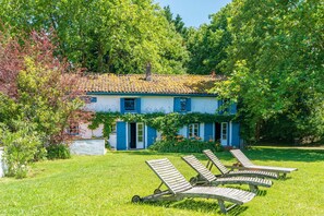 A house with a tiled roof, blue shutters, and a garden with sun loungers. - Holiday Home 'Maison De Charme Avec Jacuzzi' with Private Terrace, Private Garden and Wi-Fi (Arcangues)