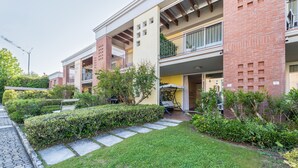 A residential building with a brick facade, balconies, and a well-maintained garden.