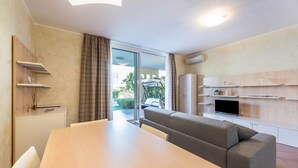 A modern living room with a sofa, a dining table, and a TV.