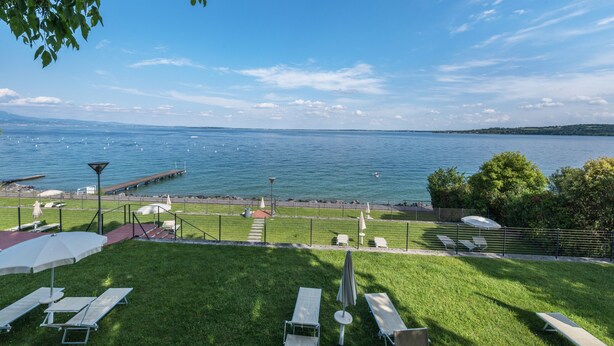 A grassy outdoor area with a view of a body of water, a dock, and a path leading to the water.
